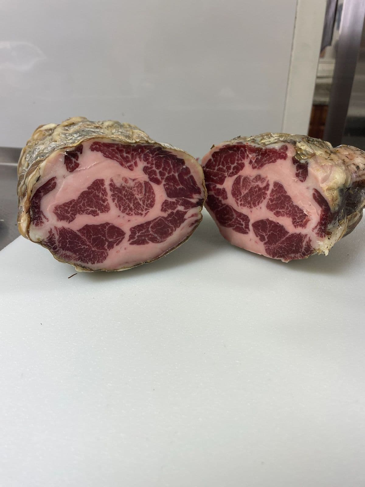 A whole coppa cut in half, showing its marbling